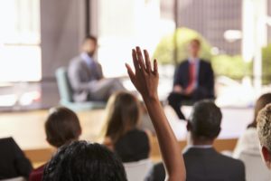 Hand in audience raised for a question at a business seminar